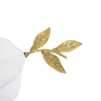 Close-up of a gold metal branch with four textured leaves, attached to a white object.
