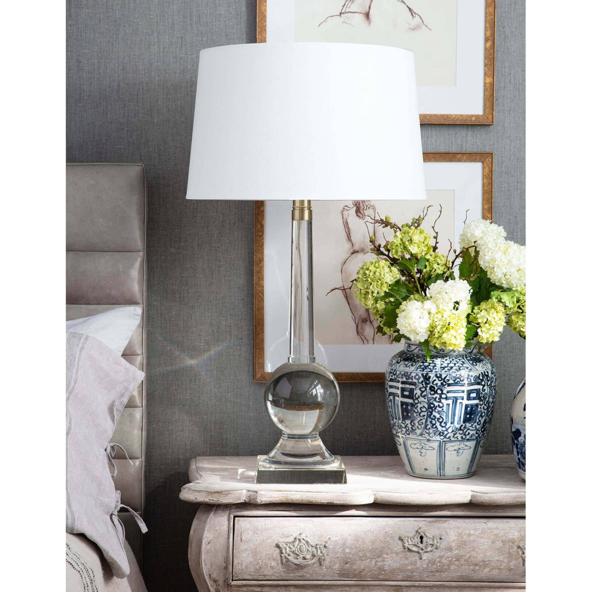 Stowe crystal table lamp with a clear sculptural base, polished brass accents, and a white linen shade.