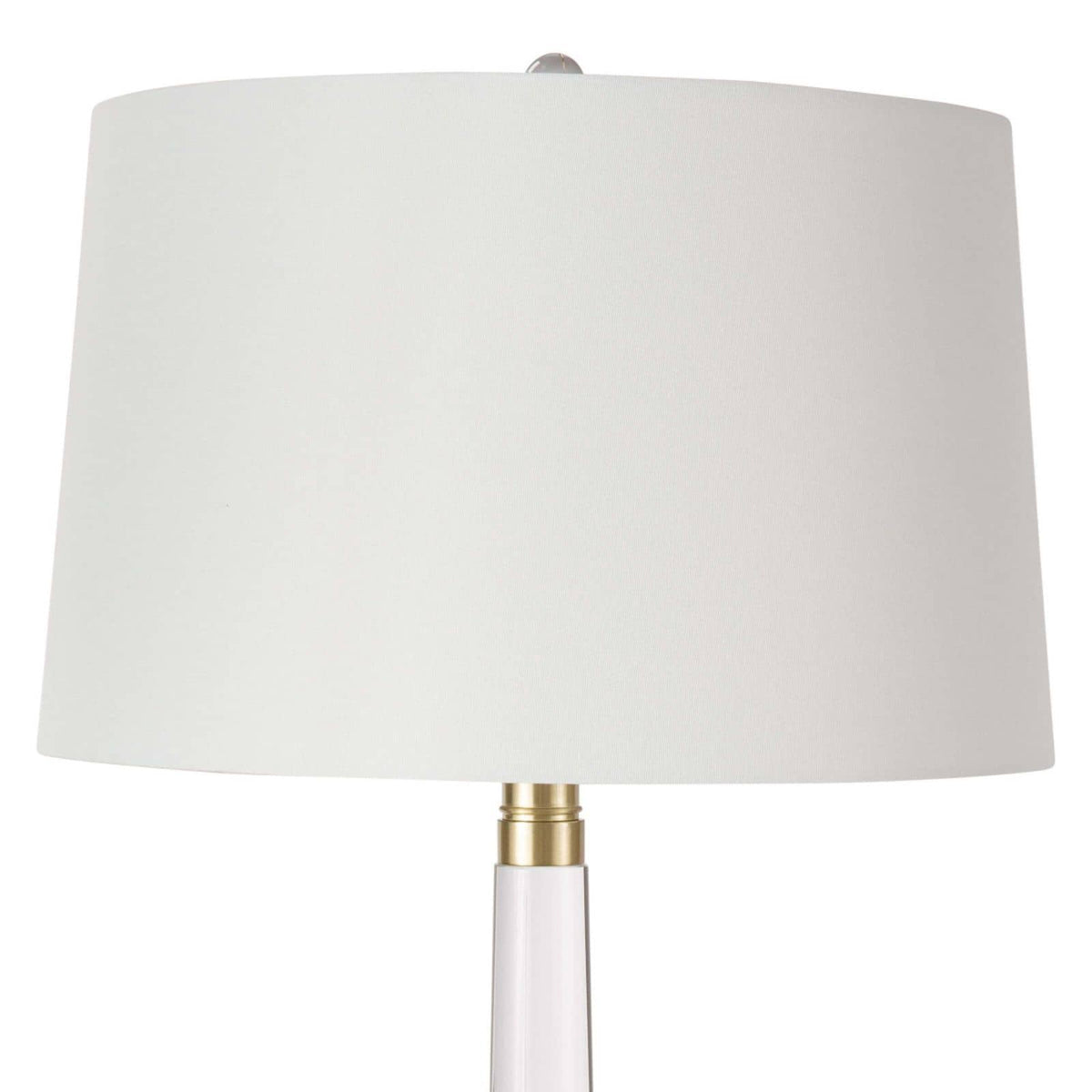 Stowe crystal table lamp with a clear sculptural base, polished brass accents, and a white linen shade.