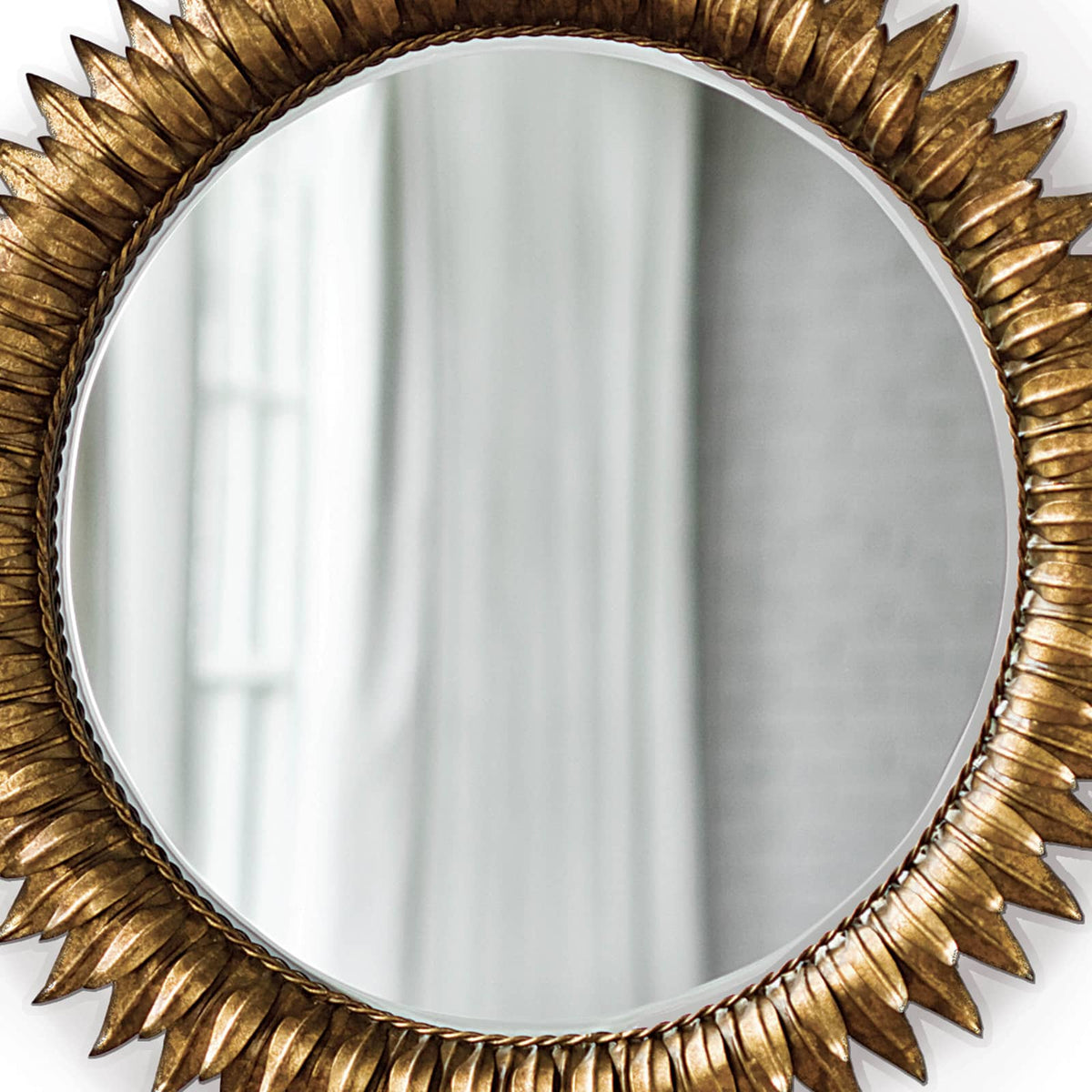 Round sunburst mirror with antiqued gold leaf frame and beveled glass.