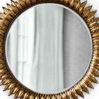 Round sunburst mirror with antiqued gold leaf frame and beveled glass.