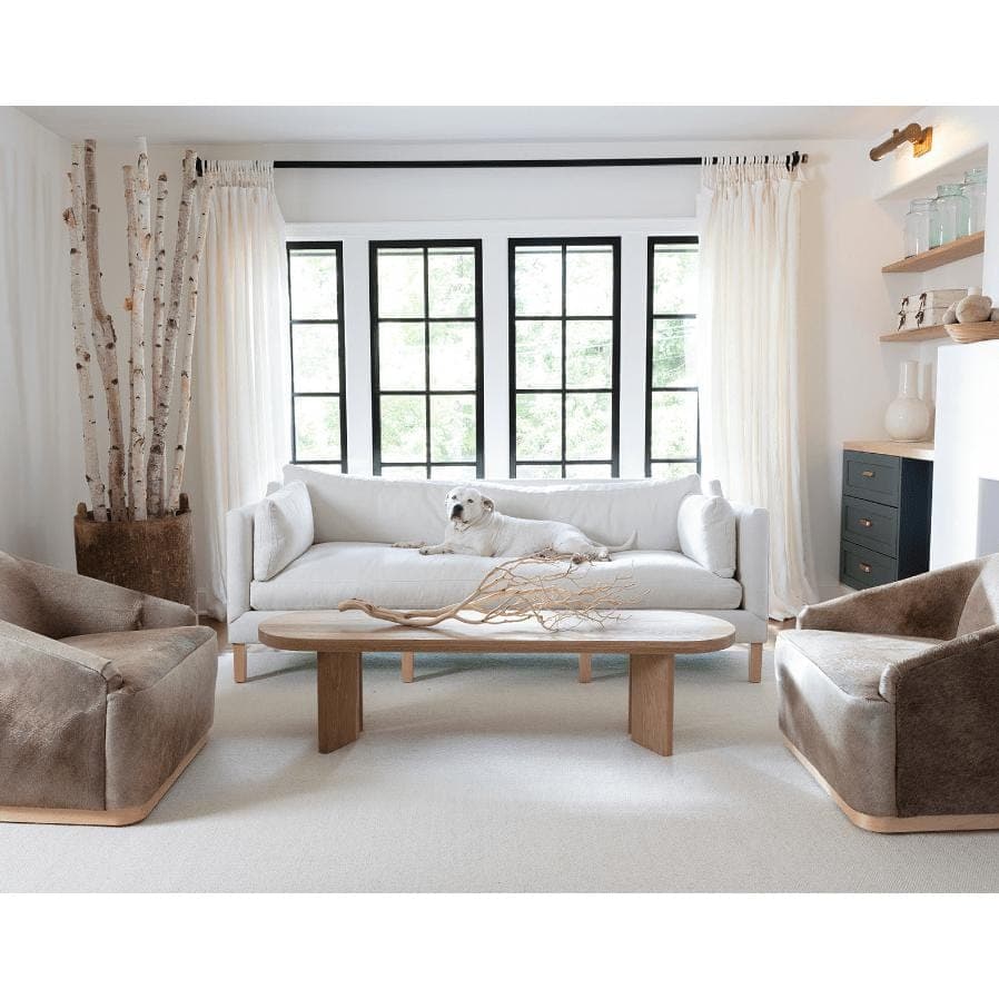 Tate Picture Light in natural brass, 18" wide, illuminating a modern living room.