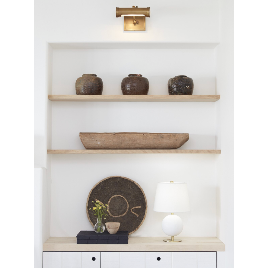 Small oil-rubbed bronze Tate Picture Light illuminating a white built-in shelf with decor.
