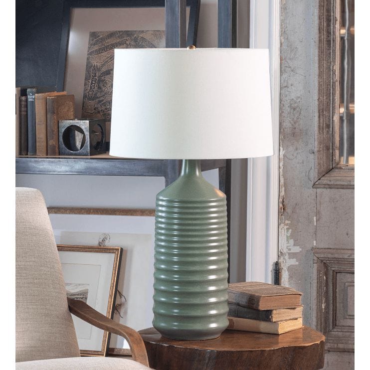 Olive green ceramic table lamp with ribbed body, natural brass neck, and tapered linen shade.