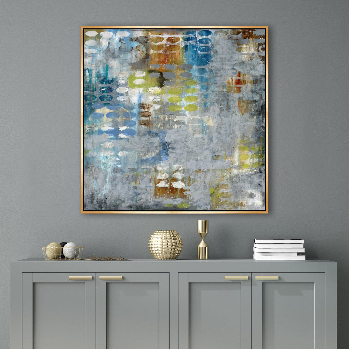 Abstract giclee canvas painting with blue, yellow, and orange tones in a gold frame over a gray cabinet.