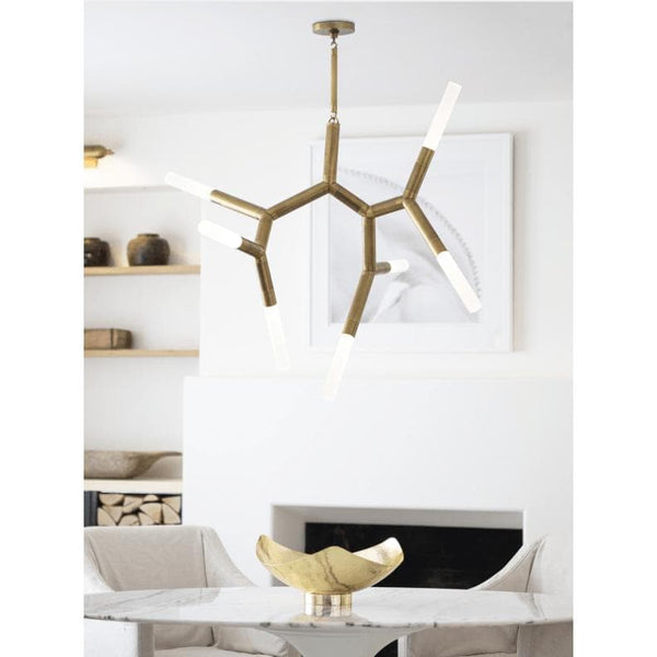 Modern Traveler Chandelier in natural brass with branching arms and frosted acrylic bulb covers, hanging over a marble table.