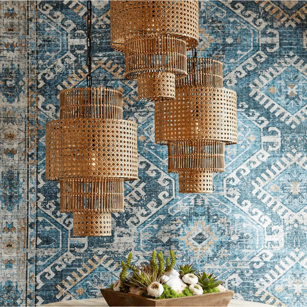 Three hand-woven, three-tier natural bamboo and rattan pendant lights against a blue patterned wall.