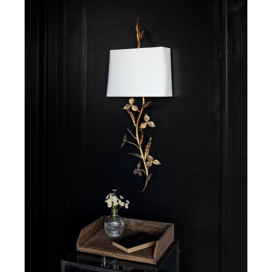 Trillium Shaded Sconce: antique gold leaf branch design with a natural linen shade on a black wall.