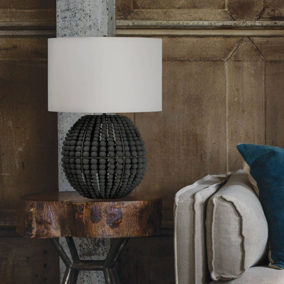Tropez table lamp with a grey beaded base and white linen shade on a rustic wooden table.