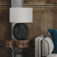 Tropez table lamp with a grey beaded base and white linen shade on a rustic wooden table.