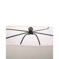 Close-up of a Tropez table lamp's oil rubbed bronze spider and finial, holding a white linen shade.