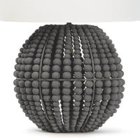 Tropez table lamp with a spherical base of distressed charcoal grey wooden beads and a white linen shade.