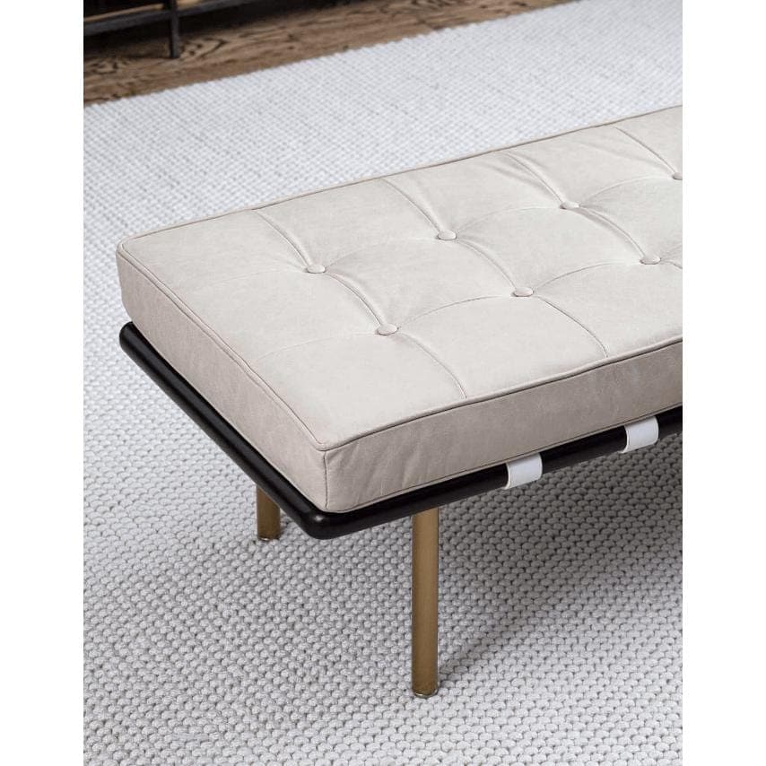 Tufted cappuccino leather gallery bench with black frame and gold legs on a white textured rug.