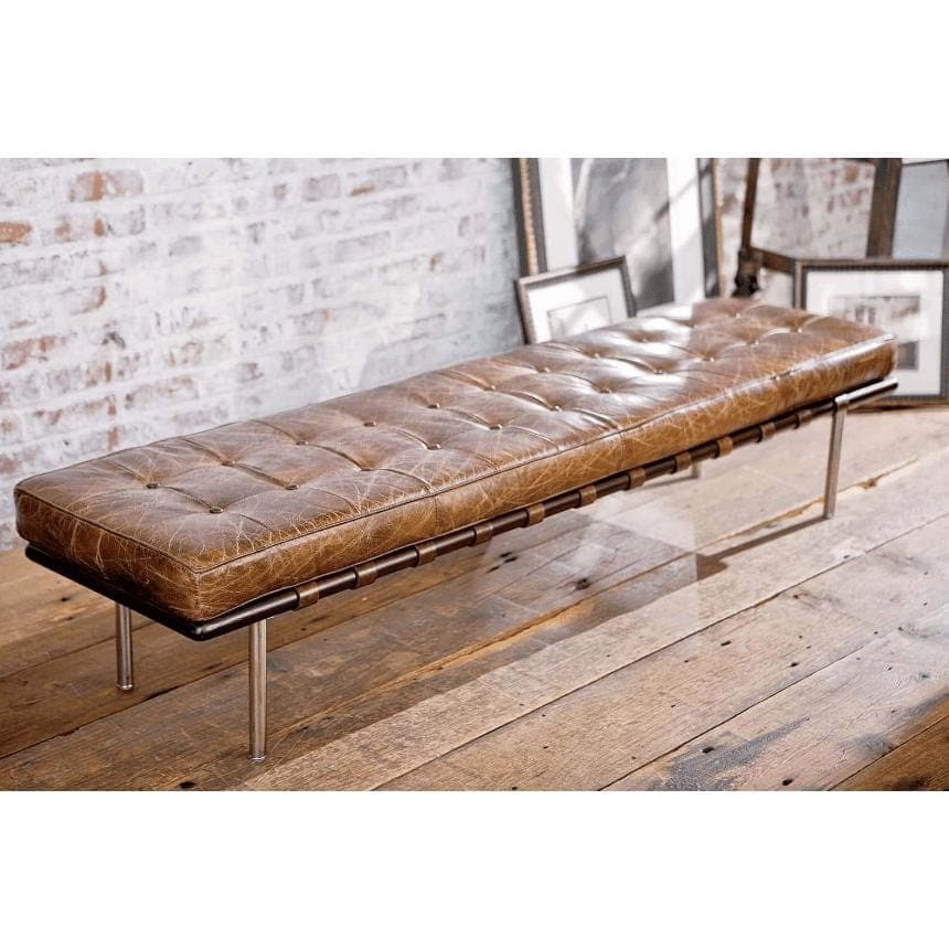 Tufted chestnut leather gallery bench with metal legs on a wooden floor.