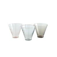 Three glass tumblers of different colors on a white background
