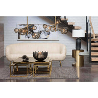 Blackened iron webbed circle decorative bowl on a glass coffee table in a modern living room.
