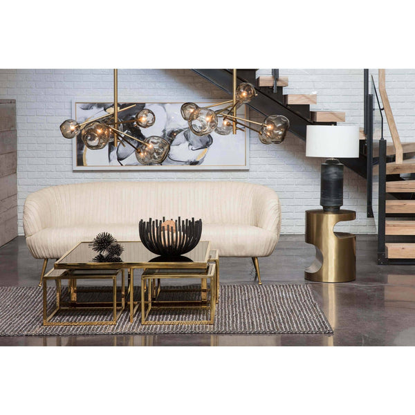 Blackened iron webbed circle decorative bowl on a glass coffee table in a modern living room.