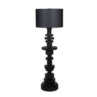 Wilton black steel floor lamp with stacked variegated metal discs base and a dark fabric drum shade.