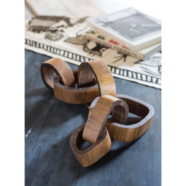 Hand-carved acacia wood links centerpiece, dark brown, on a table with a patterned runner.