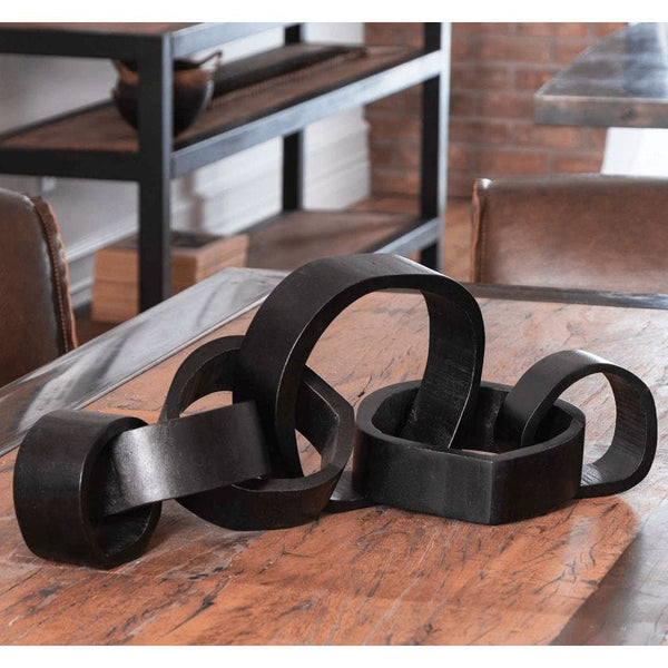 Black hand-carved acacia wood links centerpiece on a rustic wooden table.