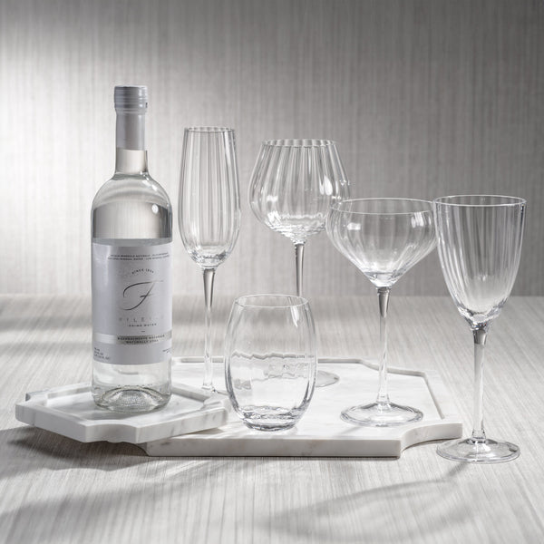 Set of wine glasses and a bottle on a marble tray with a neutral background