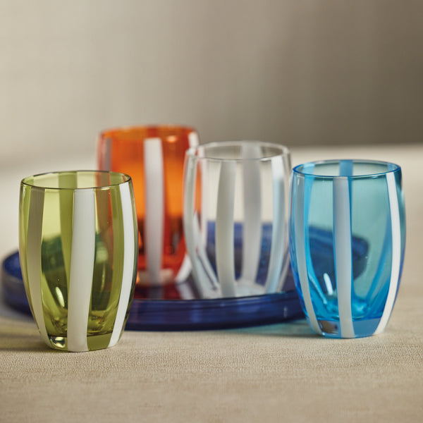 Set of colorful glass tumblers on a textured surface with a neutral background