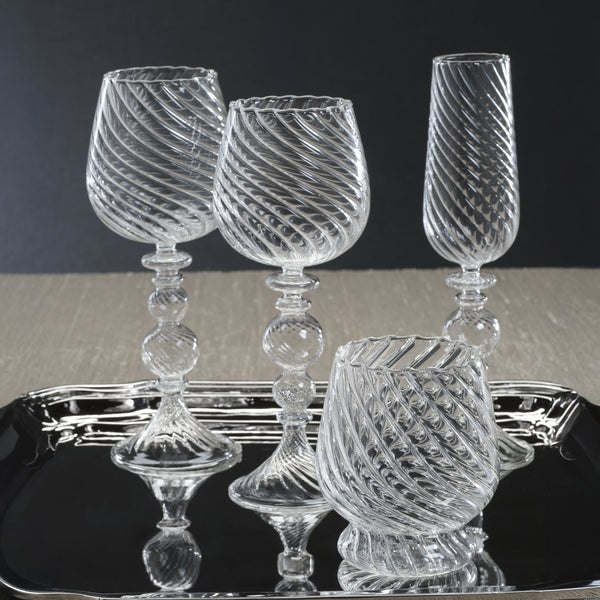 Set of clear glass goblets on a black tray with a dark background