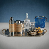 Bar tray with cocktail shakers, bottles, glasses, and snacks on a blue background