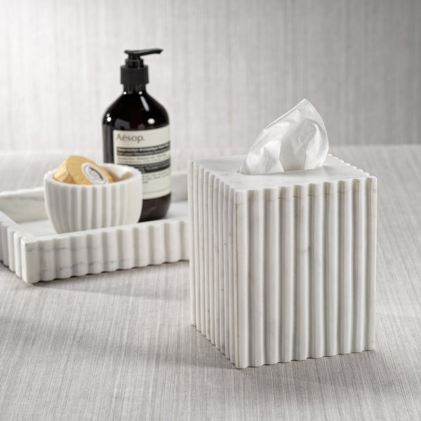 White ribbed tissue box with Aesop bottle and soap dish on a textured surface