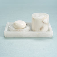 Marble soap dish with a bar of soap and a cylindrical container on a light blue background