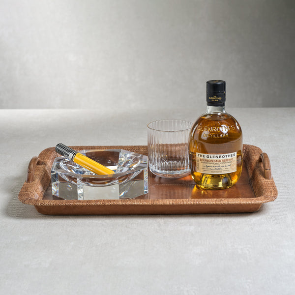Bottle of Glenrothes whiskey with a glass and ashtray on a wooden tray against a gray background