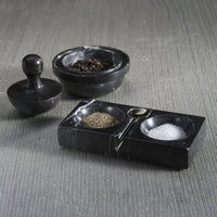 Black stone salt and pepper shaker set on a textured surface