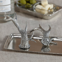 Silver deer antler salt and pepper shakers on a tray with a blurred background