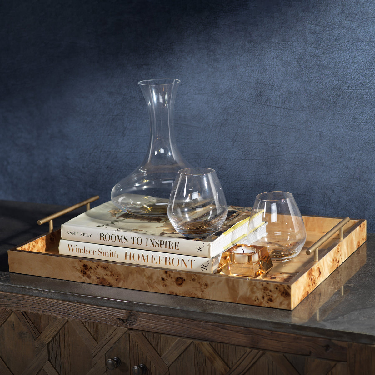 Wooden tray with decanter, glasses, and books against a dark background