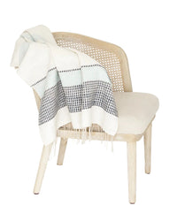 Woven chair with a patterned throw blanket on a white background