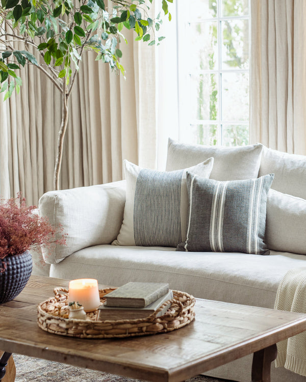 Cozy living room with a beige sofa, decorative pillows, a wooden coffee table, and a plant.