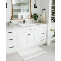 Bathroom with white vanity, marble countertop, and decorative mirror.