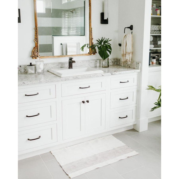 Bathroom with white vanity, marble countertop, and decorative mirror.